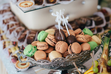Colorful macarons on pyramid-shaped plastic tower stand as part of candy bar sweet table