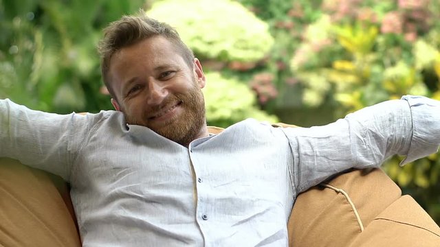 Handsome man relaxing on bean bag chair and smiling to the camera
