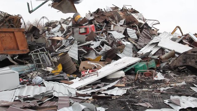 Sorting and loading of scrap metal./Excavator is loading scrap metal junk into a bin at a garbage dump or recycling center.