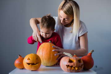 Young woman carving a pumpkin for Haloween with her son