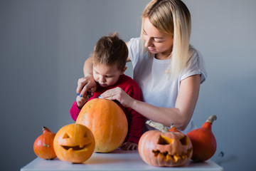 Fototapeta na wymiar Mother helping her son to carve pumpkin