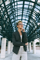 Fototapeta premium Young happy business woman standing in front of big modern building. She smiling and talking on her cell phone.