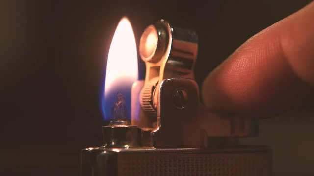Slow Mo. Lighter sparking many times in male hand. Close up of lighting fire with a petrol cigarette lighter in the darkness