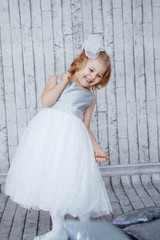 little girl in beautiful white dress on a light wooden background. Shine, silver, Xmas