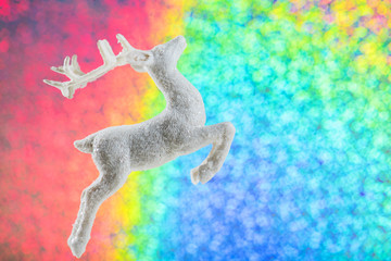 Obraz na płótnie Canvas Christmas decoration, white deer on the rainbow color background with copy space. festive xmas banner