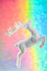 Obraz na płótnie Canvas Christmas decoration on the rainbow color background. Shiny white deer on festive background with copy space