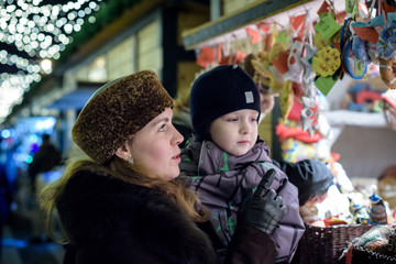 Happy family spend time at a Christmas street market fair in the old town of Salzburg, Austria. Holidays, , concept. Mother and son winter outdoor among decorations