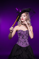 Beautiful woman, blonde in a good witch costume on a purple background holds a magic wand. Costume...