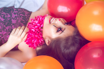 Happy teen girl lying between colorful balloons. Party