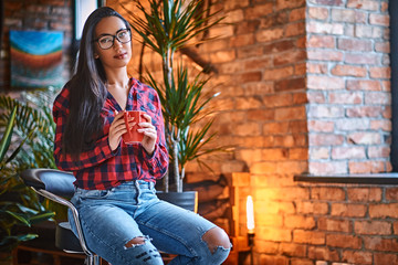 A woman drinks coffee in a room with loft interior.