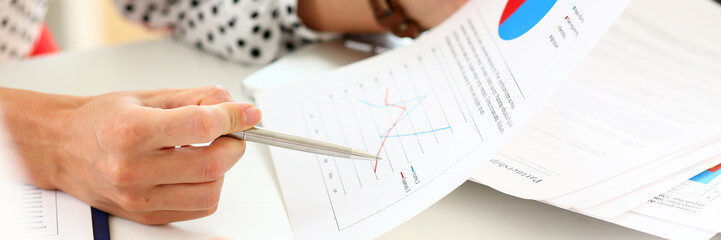 Female arm holding silver pen point in financial graph