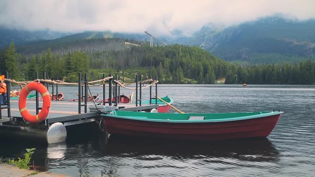 Boat on the dock surrounded mountains. Fantastic Mountain lake (Strbske Pleso) in High Tatras. Slovakia, Europe. Foggy forest in the background. Beauty world, holidays, travel, recreation. Full HD
