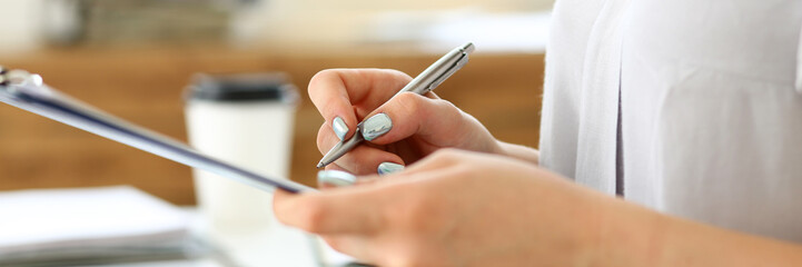 Female arm in suit hold silver pen and pad