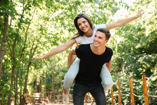Young smiling couple enjoying piggyback ride and laughing