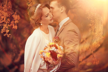 Newlyweds groom and bride walking in autumn park