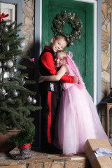 Brother and sister are hugging at the door of the house at Christmas