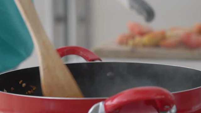 Woman mixing ingredients on frying pan and chopping tomatoes, steadycam shot
