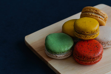 Colorful French macaron or Italian macaron stack on cutting board. Homemade delicious macaron on granite table with copy space for background or wallpaper. French dessert for served with tea or coffee
