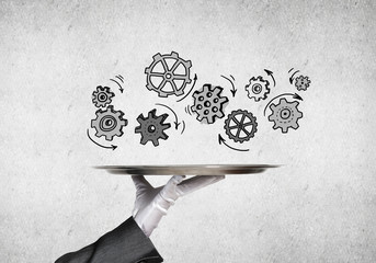 Waiter hand with empty silver tray and drawn gears concept