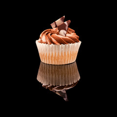 One muffin cupcake with brown cream and pieces of chocolate