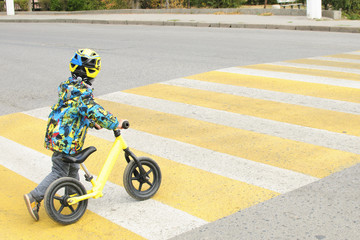 A boy with a bicycle crosses a pedestrian crossing with yellow markings