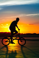 A guy shows tricks on a bicycle at sunset