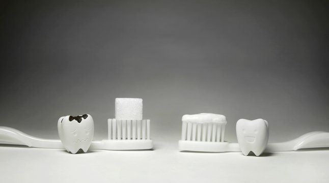 Decayed tooth Model with Cube Sugar on White toothbrush And Happy Emotion Teeth Model and White toothbrush and Toothpaste conflict between Good and Bad Dental Healthy