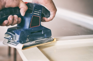 Orbital sander in use, sanding old door for a new lick of paint.