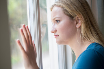 Sad Young Woman Suffering From Depression Looking Out Of Window