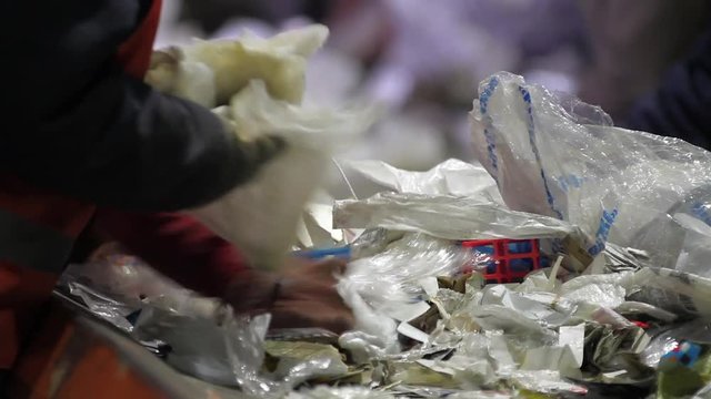 Sorting paper and plastic on a conveyor belt in a recycling facility. Trash workers sorting trash, garbage at a recycling plant conveyor. Workers at conveyor sorting garbage at a recycling plant.
