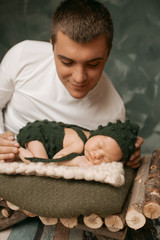 Father holds tender his little baby while she sleeps in little wooden bed