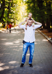 Cheerful dad holds his daughter on the neck