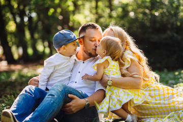 Lovely family pose with their happy children in the rays of summer sun