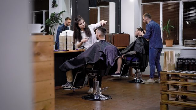 The process of hair cutting in barbershop, several hairdressers make stylish and fashionable hairstyles in the men's beauty salon