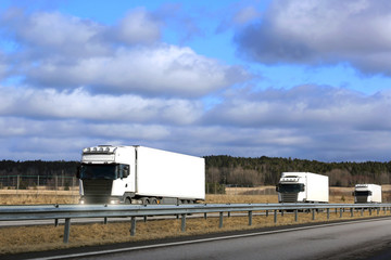 Three White Semi Trucks Platoon on Freeway