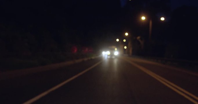 Van driving on a dark street at night in an urban city, in slow motion