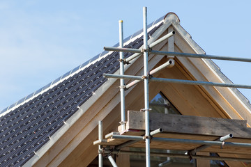 Naklejka premium Modern house roof construction. Black curved ceramic tiles with scaffolding.