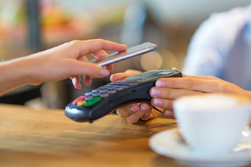 Customer Paying Through Mobile Phone In Cafe
