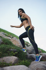 Fitness woman climbing up the stone hill of the city park