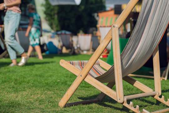 Sunbed On Green Park With Relaxing People. Garden Lounge For Sunbathing And Rest