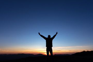 Fototapeta na wymiar Victoire d'un homme au sommet d'une montagne au coucher de soleil