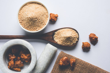 Asafoetida cake and powder or Hing or Heeng which is an important ingredient in Indian food recipes with big wooden spoon and mortar, selective focus