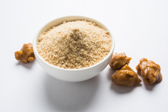 Asafoetida cake and powder or Hing or Heeng which is an important ingredient in Indian food recipes with big wooden spoon and mortar, selective focus