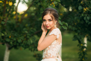 Young girl in wedding dress in park posing for photographer. Sunny weather, summer.