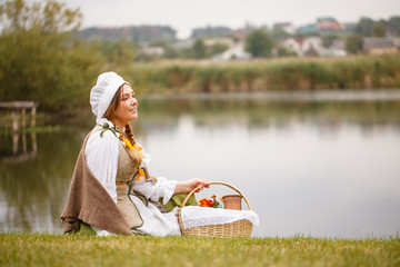 a peasant woman with a basket sits by the river