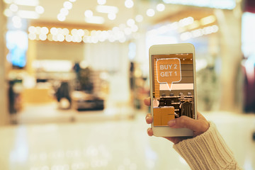 Close-up shot of young woman using smartphone with augmented reality app while doing shopping at...