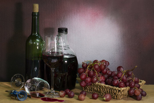 Bottle wine with wine glass and grape in basket  on the plank in dim light room