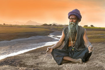 Sadhu meditation near river - obrazy, fototapety, plakaty