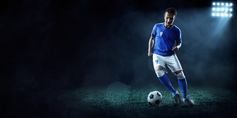 Soccer player performs an action play on a dark background. Player wears unbranded sport uniform.