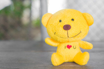 yellow teddy bear sitting on wood floor with blur background